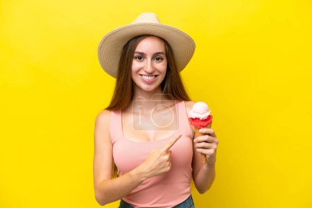 Téléchargez les photos : Young caucasian with a cornet ice cream isolated on yellow background pointing to the side to present a product - en image libre de droit