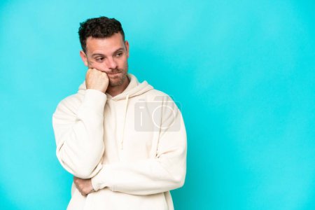 Photo for Young caucasian handsome man isolated on blue background with tired and bored expression - Royalty Free Image