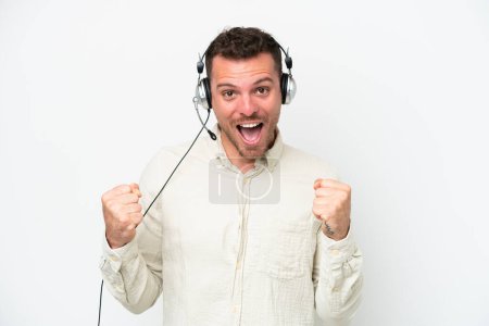 Photo for Telemarketer caucasian man working with a headset isolated on white background celebrating a victory in winner position - Royalty Free Image