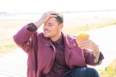 Photo for Young caucasian man holding fried chips at outdoors has realized something and intending the solution - Royalty Free Image