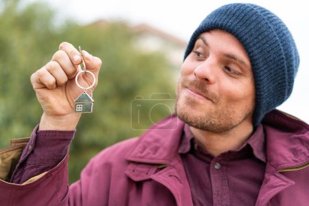 Photo for Young caucasian man holding home keys at outdoors - Royalty Free Image