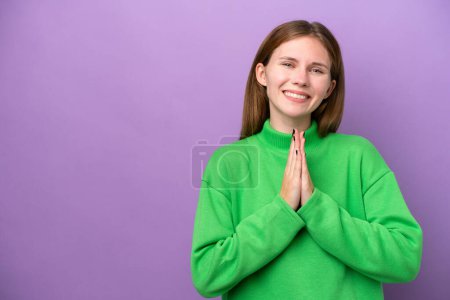 Photo for Young English woman isolated on purple background keeps palm together. Person asks for something - Royalty Free Image