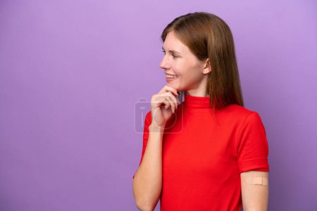 Téléchargez les photos : Jeune femme anglaise portant des pansements isolés sur fond violet pensant une idée et regardant côté - en image libre de droit
