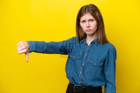 Téléchargez les photos : Jeune femme anglaise isolée sur fond jaune montrant pouce vers le bas avec expression négative - en image libre de droit