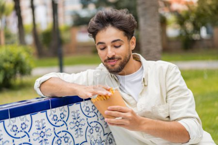 Photo for Young Arabian handsome man holding fried chips at outdoors - Royalty Free Image