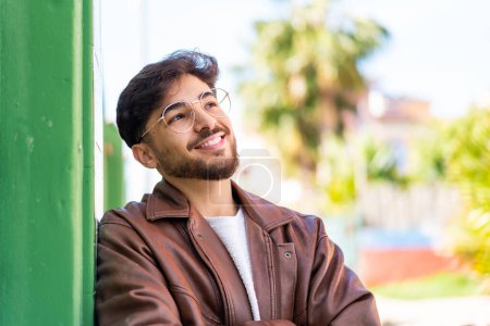 Foto de Hombre árabe guapo al aire libre mirando hacia arriba mientras sonríe - Imagen libre de derechos