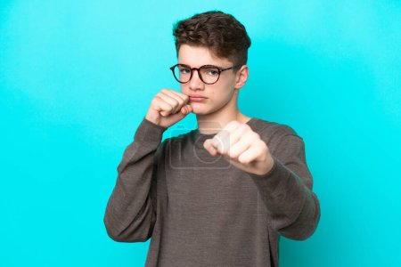 Photo for Teenager Russian man isolated on blue background with fighting gesture - Royalty Free Image