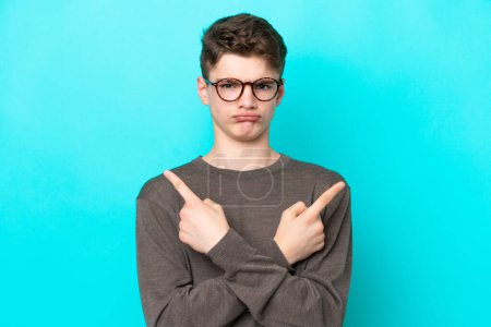 Photo for Teenager Russian man isolated on blue background pointing to the laterals having doubts - Royalty Free Image