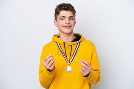 Téléchargez les photos : Adolescent russe l'homme avec médailles isolé sur blanc fond faire de l'argent geste - en image libre de droit