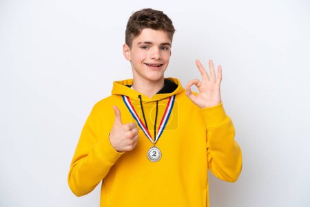 Foto de Adolescente ruso hombre con medallas aisladas sobre fondo blanco mostrando signo ok y el pulgar hacia arriba gesto - Imagen libre de derechos