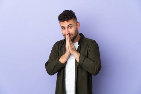 Photo for Caucasian man isolated on purple background keeps palm together. Person asks for something - Royalty Free Image