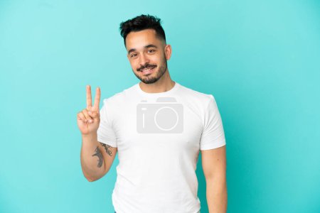 Photo for Young caucasian man isolated on blue background smiling and showing victory sign - Royalty Free Image