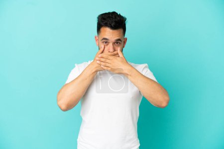Photo for Young caucasian man isolated on blue background covering mouth with hands - Royalty Free Image