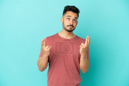 Photo for Young caucasian man isolated on blue background with fingers crossing and wishing the best - Royalty Free Image