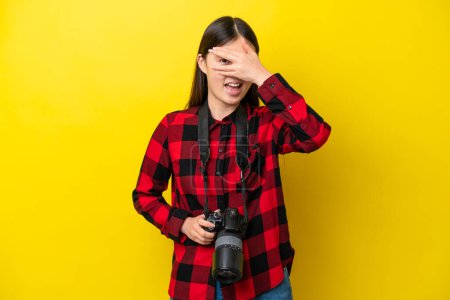 Photo for Young photographer Chinese woman isolated on yellow background covering eyes by hands and smiling - Royalty Free Image