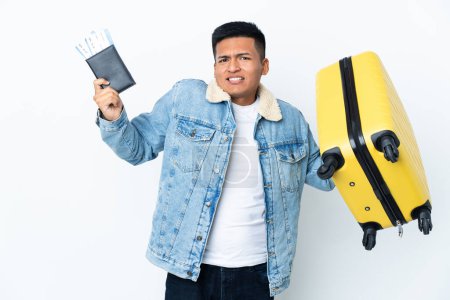 Foto de Joven ecuatoriano aislado sobre fondo blanco infeliz en vacaciones con maleta y pasaporte - Imagen libre de derechos