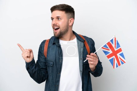 Foto de Joven hombre caucásico sosteniendo una bandera del Reino Unido aislado sobre fondo blanco con la intención de realizar la solución mientras levanta un dedo - Imagen libre de derechos