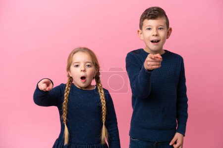 Photo for Little caucasian brothers isolated on pink background surprised and pointing front - Royalty Free Image