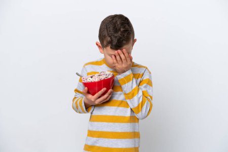 Téléchargez les photos : Petit garçon caucasien tenant un bol de céréales isolé sur fond blanc avec une expression fatiguée et malade - en image libre de droit