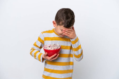Téléchargez les photos : Petit garçon caucasien tenant un bol de céréales isolé sur fond blanc riant - en image libre de droit