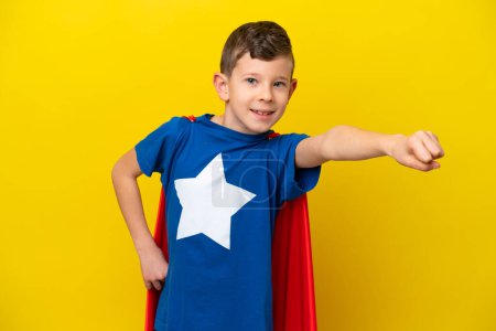 Photo for Little caucasian boy isolated on yellow background in superhero costume with proud gesture - Royalty Free Image