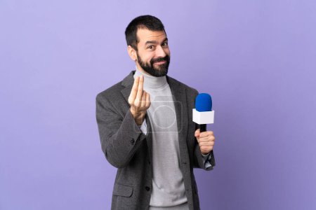 Erwachsener Reporter Mann mit Bart hält ein Mikrofon über isolierten lila Hintergrund macht Geld Geste