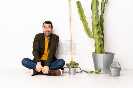 Photo for Gardener man sitting on the floor at indoors with surprise facial expression - Royalty Free Image