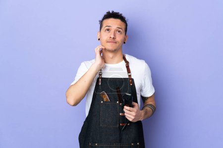 Barber man in an apron over isolated purple background thinking an idea