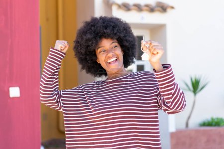 Téléchargez les photos : Afro-Américaine tenant les clés de la maison à l'extérieur célébrant une victoire - en image libre de droit