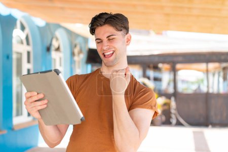 Photo for Young handsome man holding a tablet at outdoors celebrating a victory - Royalty Free Image
