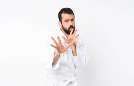 Foto de Joven haciendo karate sobre fondo blanco aislado nervioso estirando las manos al frente - Imagen libre de derechos