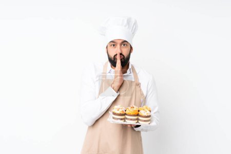 Photo for Young man holding muffin cake over isolated white background keeps palm together. Person asks for something - Royalty Free Image