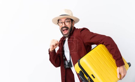 Foto de Hombre viajero con barba sosteniendo una maleta sobre un fondo blanco aislado corriendo rápido - Imagen libre de derechos