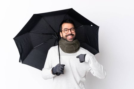 Téléchargez les photos : Homme beau caucasien avec barbe tenant un parapluie sur mur blanc isolé avec expression faciale surprise - en image libre de droit