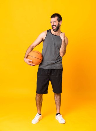 Photo for Full-length shot of man over isolated yellow background playing basketball - Royalty Free Image