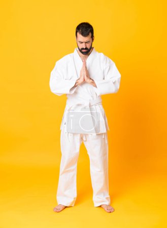 Photo for Full-length shot of man over isolated yellow background doing karate and saluting - Royalty Free Image