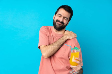 Photo for Young man over holding a cocktail over isolated blue background suffering from pain in shoulder for having made an effort - Royalty Free Image