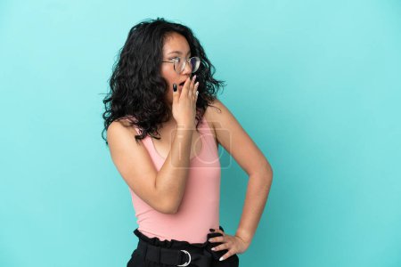 Téléchargez les photos : Jeune femme asiatique isolé sur fond bleu faisant geste surprise tout en regardant sur le côté - en image libre de droit