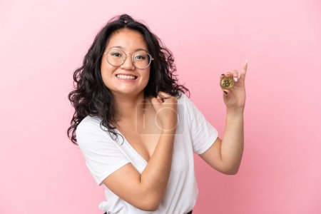 Photo for Young asian woman holding a Bitcoin isolated on pink background celebrating a victory - Royalty Free Image