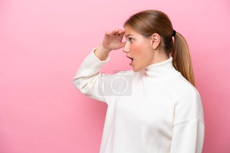 Photo for Young caucasian woman isolated on pink background with surprise expression while looking side - Royalty Free Image