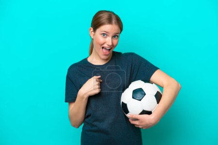 Téléchargez les photos : Jeune joueur de football femme isolée sur fond bleu avec expression faciale surprise - en image libre de droit