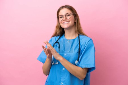 Foto de Joven cirujana doctora aislada sobre fondo rosa aplaudiendo tras presentación en conferencia - Imagen libre de derechos