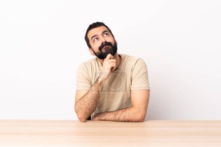 Foto de Caucásico hombre con barba en una mesa y mirando hacia arriba. - Imagen libre de derechos