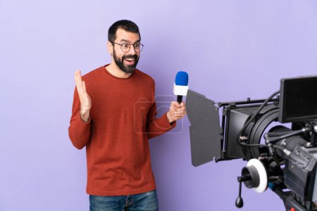 Téléchargez les photos : Reporter homme tenant un microphone et rapportant des nouvelles sur fond violet isolé avec expression faciale surprise - en image libre de droit