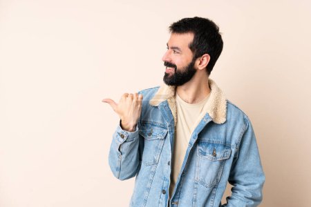 Téléchargez les photos : Homme caucasien avec barbe sur fond isolé pointant vers le côté pour présenter un produit - en image libre de droit