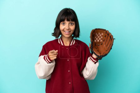 Téléchargez les photos : Jeune joueuse mixte femme avec gant de baseball isolé sur fond bleu surpris et pointant devant - en image libre de droit