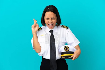 Téléchargez les photos : Jeune pilote d'avion sur fond bleu isolé avec doigts croisés - en image libre de droit