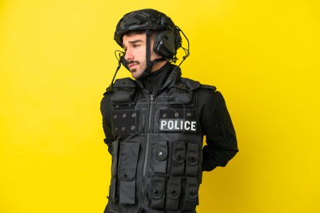 Téléchargez les photos : SWAT homme caucasien isolé sur fond jaune souffrant de maux de dos pour avoir fait un effort - en image libre de droit