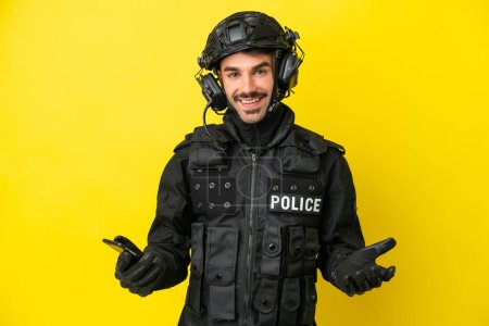 Téléchargez les photos : SWAT homme caucasien isolé sur fond jaune garder une conversation avec le téléphone portable avec quelqu'un - en image libre de droit