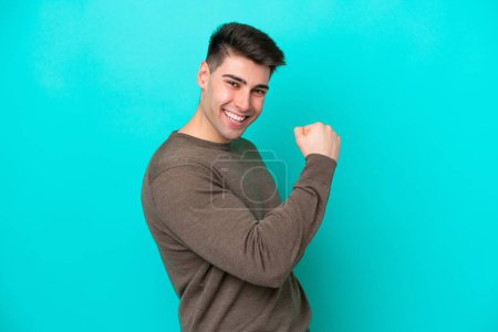 Photo for Young caucasian man isolated on blue background celebrating a victory - Royalty Free Image